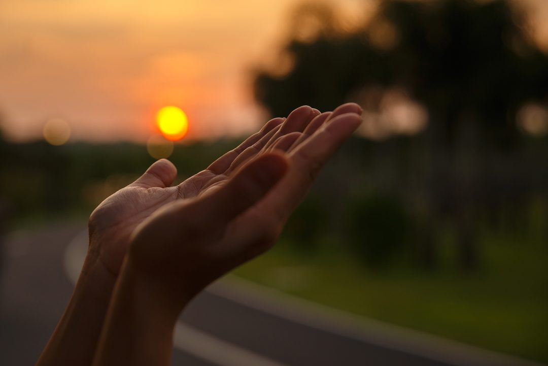 Praying hands with sunrise in the background